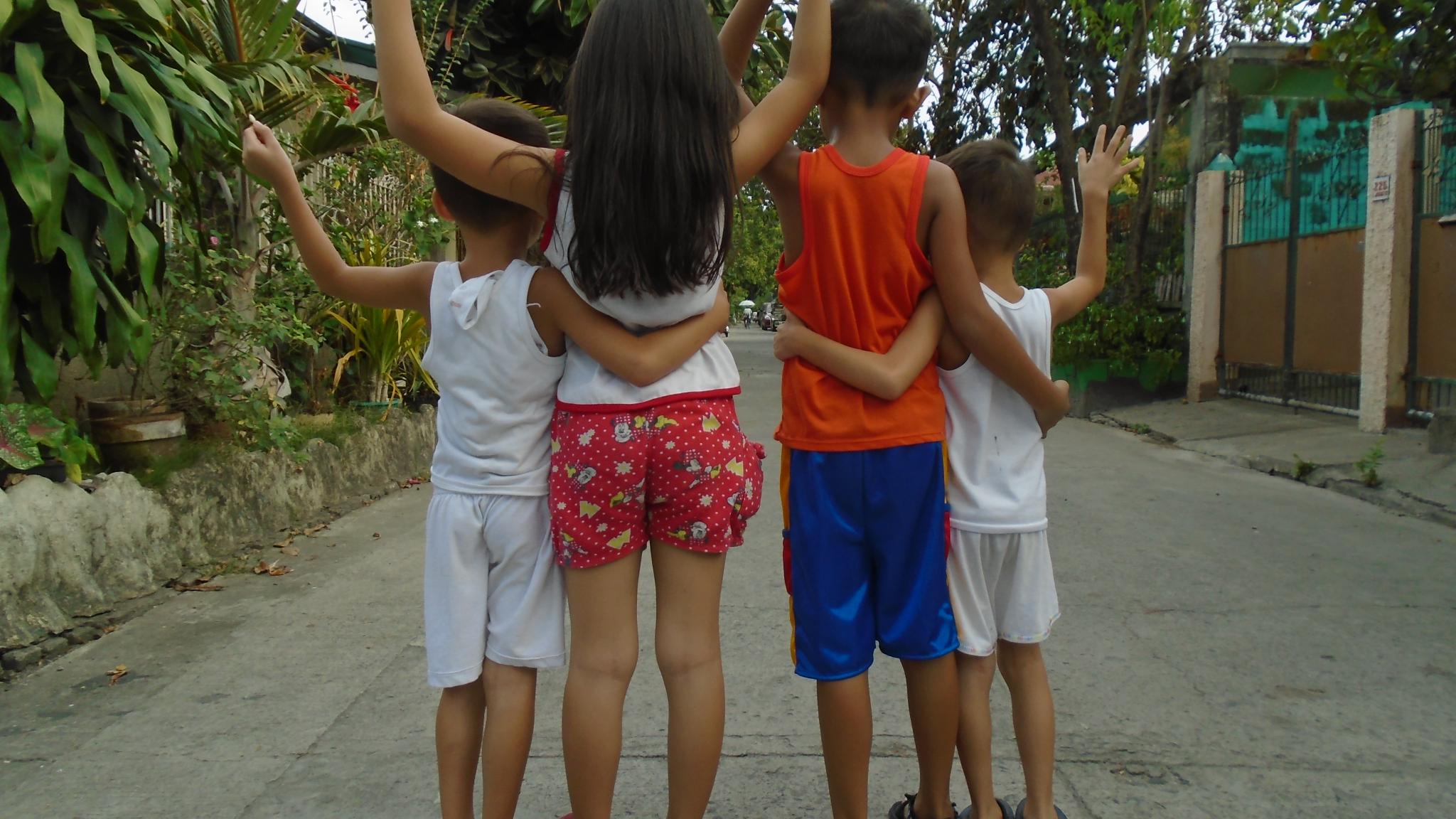 Picture of 4 children standing together with their back facing the camera