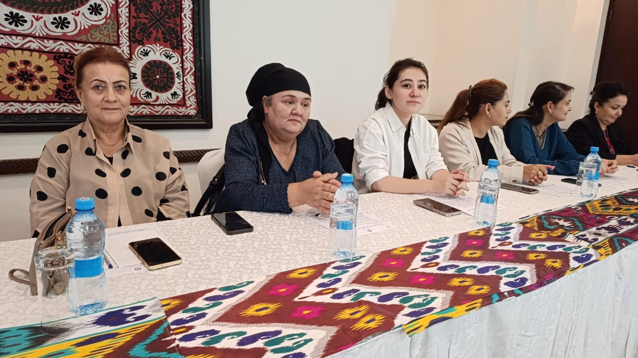 6 women sitting behind a desk attending a meeting.